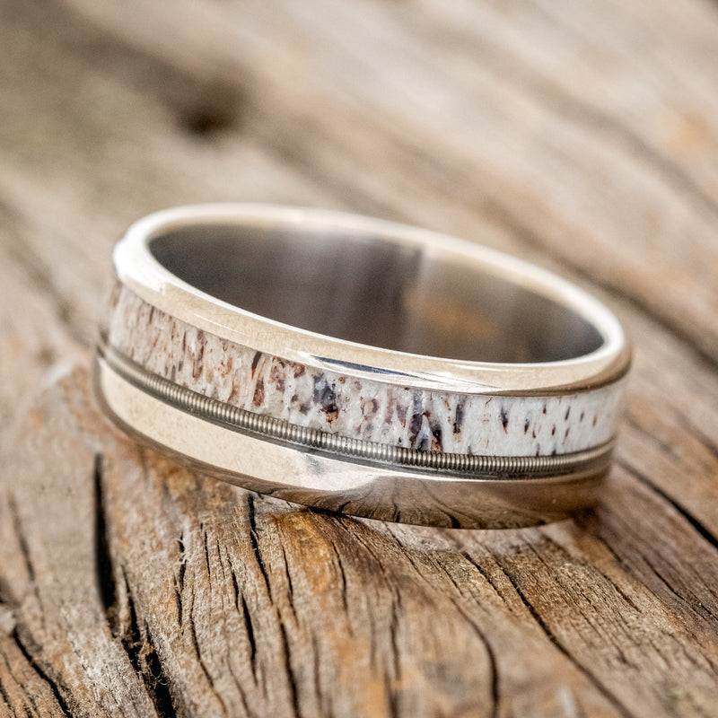 Shown here is "Tanner", a custom, handcrafted men's wedding ring featuring a naturally shed elk antler and guitar string inlay, tilted left. Additional inlay options are available upon request.