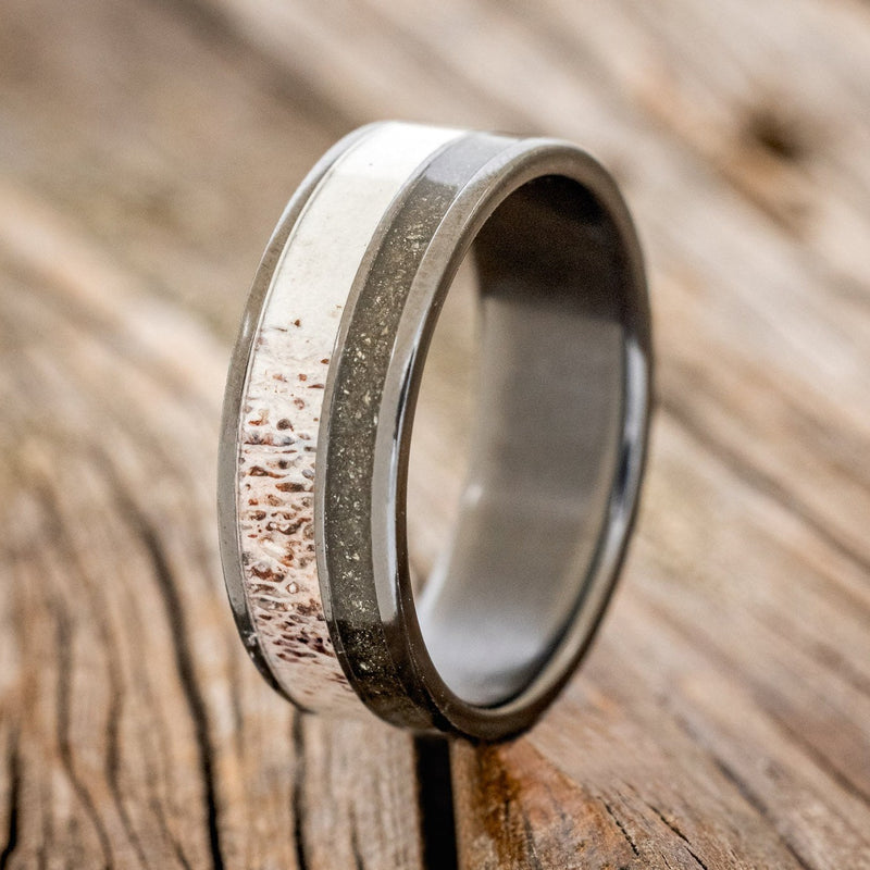 Shown here is "Raptor", a custom, handcrafted men's wedding ring featuring elk antler and iron ore inlays, upright facing left. Additional inlay options are available upon request.