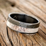 Shown here is "Raptor", a custom, handcrafted men's wedding ring featuring elk antler and iron ore inlays on a titanium band, tilted left. Additional inlay options are available upon request.