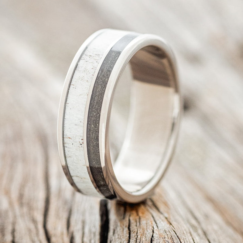 Shown here is "Raptor", a custom, handcrafted men's wedding ring featuring elk antler and iron ore inlays on a titanium band, upright facing left. Additional inlay options are available upon request.