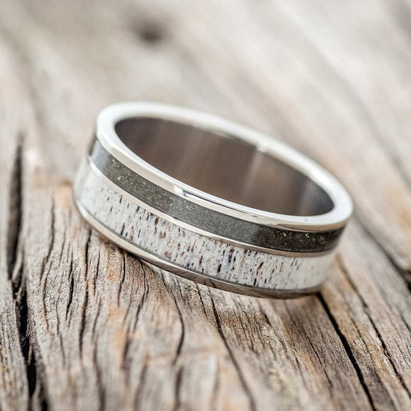 Shown here is "Raptor", a custom, handcrafted men's wedding ring featuring elk antler and iron ore inlays on a titanium band, tilted left. Additional inlay options are available upon request.