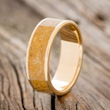 Shown here is "Rainier", a handcrafted men's wedding ring featuring an amber inlay on a 14K gold band, upright facing left. Additional inlay options are available upon request.
