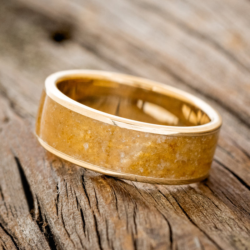 Shown here is "Rainier", a handcrafted men's wedding ring featuring an amber inlay on a 14K gold band, tilted left. Additional inlay options are available upon request.