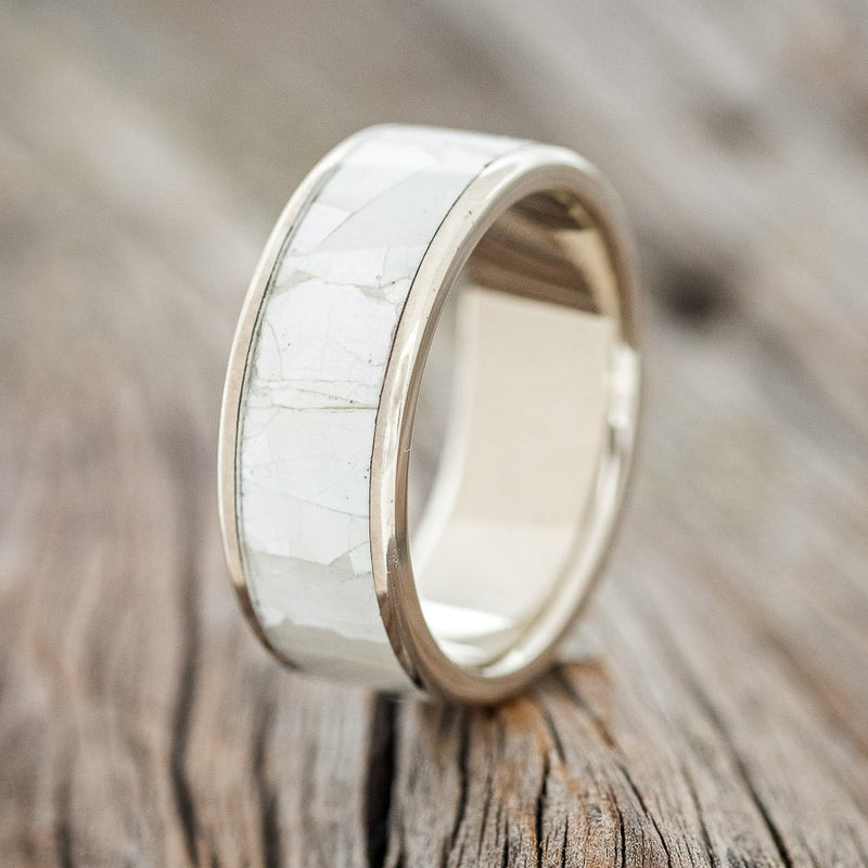 Shown here is "Rainier", a handcrafted men's wedding ring featuring a mother of pearl inlay on a 14K gold band, upright facing left. Additional inlay options are available upon request.