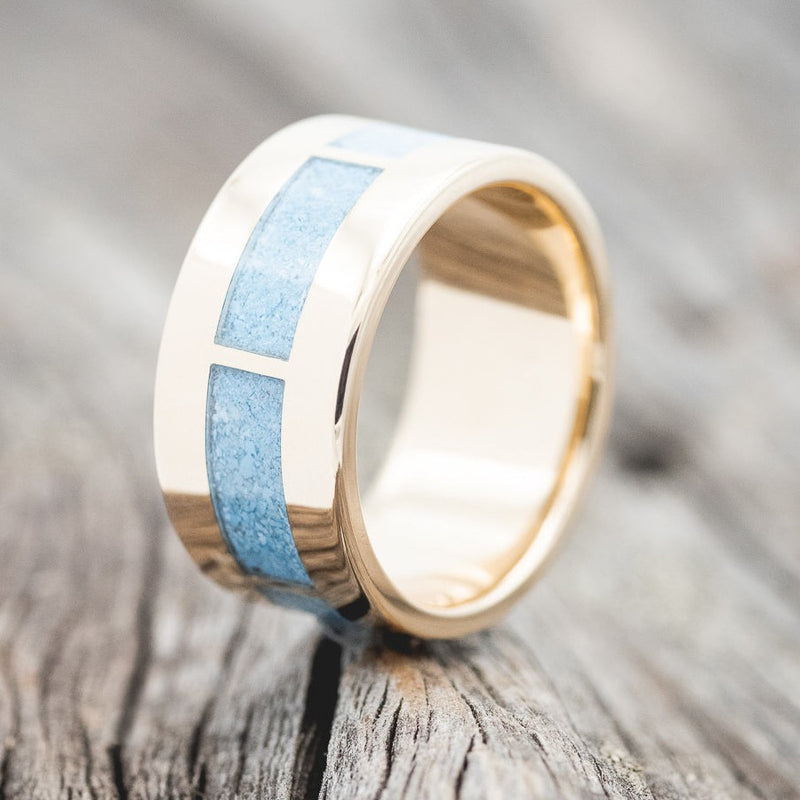 Shown here is "Thor", a unique men's wedding ring featuring a 14K gold band with turquoise inlays in the front section, while the back section has a solid gold portion allowing for future resizes if needed, upright facing left. Additional inlay options are available upon request.