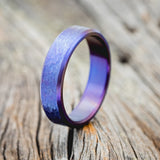 Shown here is a handcrafted men's wedding ring featuring a fire-treated titanium band with a hammered finish, upright facing left.
