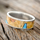 Shown here is "Rainier", a handcrafted men's wedding ring featuring buckeye burl wood as the base material with turquoise and copper inlays set into the burls, tilted left. Additional inlay options are available upon request.