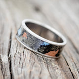 Shown here is "Rainier", a handcrafted men's wedding ring featuring buckeye burl wood with turquoise and copper inlays set into the burls, tilted left.