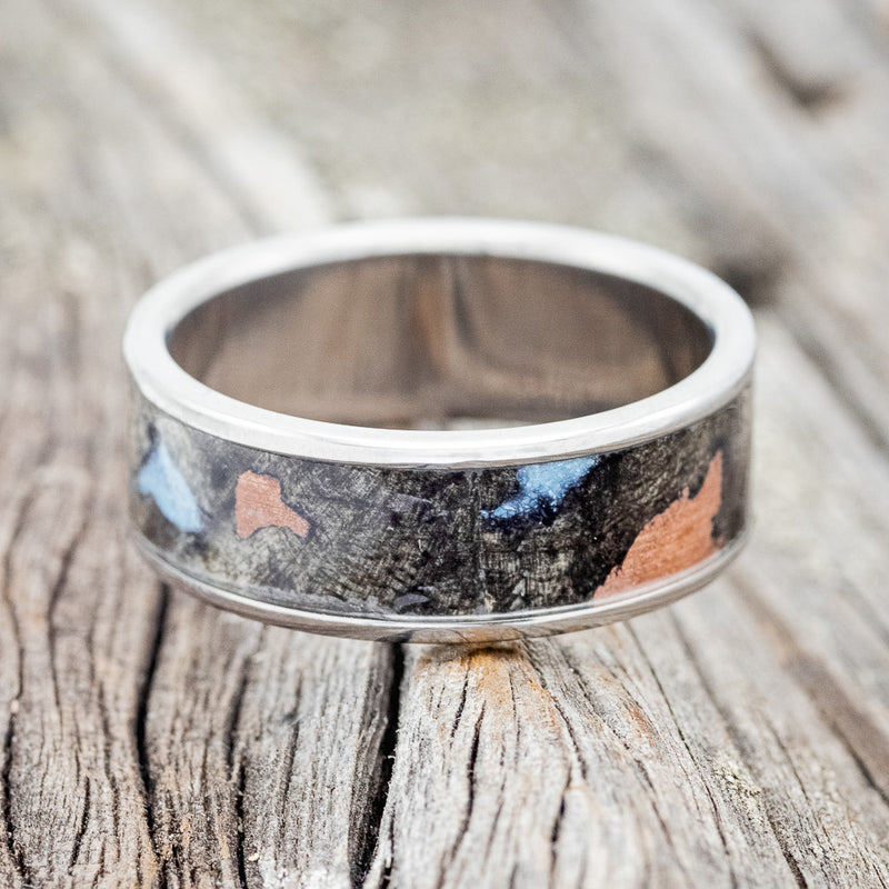 Shown here is "Rainier", a handcrafted men's wedding ring featuring buckeye burl wood as the base material with turquoise and copper inlays set into the burls, laying flat. Additional inlay options are available upon request.