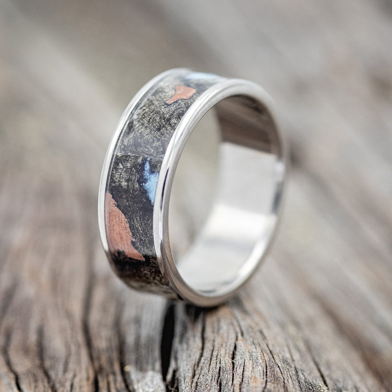 Shown here is "Rainier", a handcrafted men's wedding ring featuring buckeye burl wood with turquoise and copper inlays set into the burls, upright facing left. 