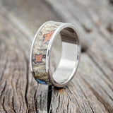 Shown here is "Rainier", a handcrafted men's wedding ring featuring buckeye burl wood with turquoise and copper inlays set into the burls, upright facing left.