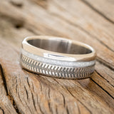 Shown here is "Vertigo", a custom engraved tire tread men's wedding ring featuring a diamond dust inlay, tilted left. Additional inlay options are available upon request.