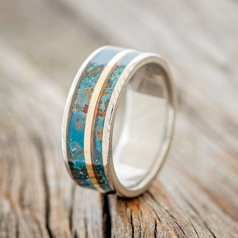 Shown here is "Raptor", a handcrafted men's wedding ring featuring two channels of patina copper and a 14K yellow gold inlay, upright facing left. Additional inlay options are available upon request.