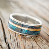 Shown here is "Raptor", a handcrafted men's wedding ring featuring two channels of patina copper and a 14K yellow gold inlay, tilted left. Additional inlay options are available upon request.