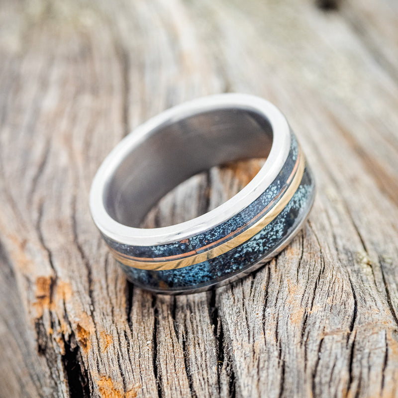 Shown here is "Raptor", a handcrafted men's wedding ring featuring two channels of patina copper and a 14K yellow gold inlay, tilted right. Additional inlay options are available upon request.