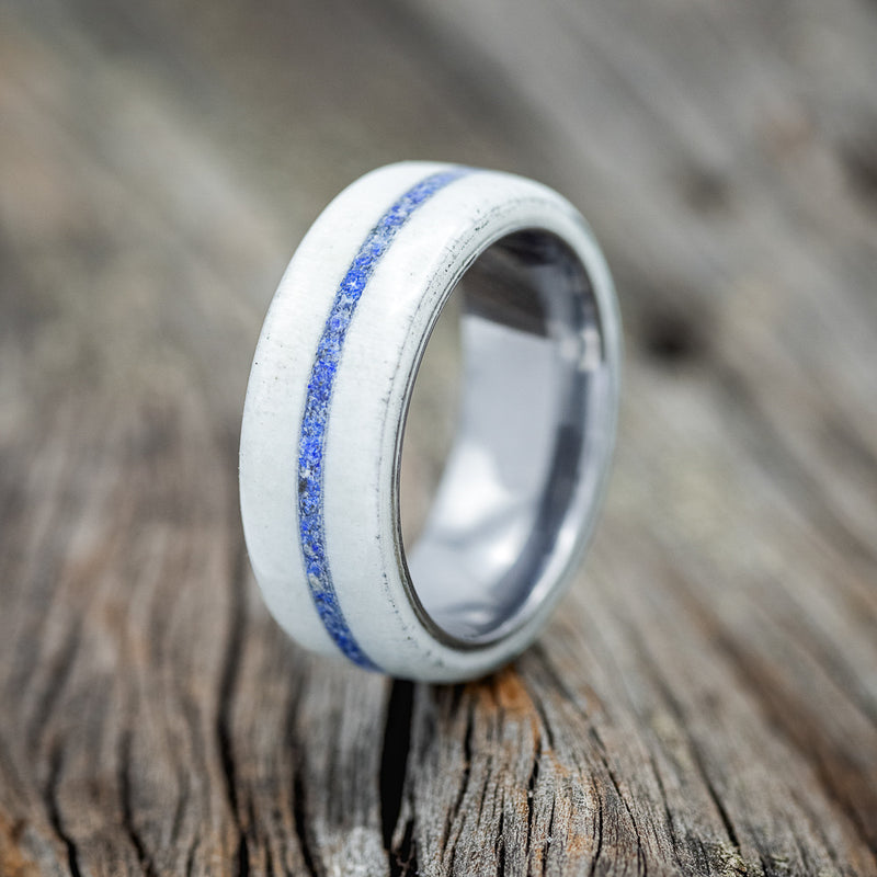 Shown here is "Remmy", a handcrafted men's wedding ring featuring an antler overlay and a centered lapis lazuli inlay, upright facing left.