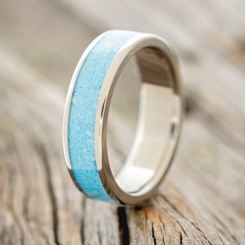 Shown here is "Rainier", a custom, handcrafted men's wedding ring featuring a crushed turquoise inlay, upright facing left. Additional inlay options are available upon request.