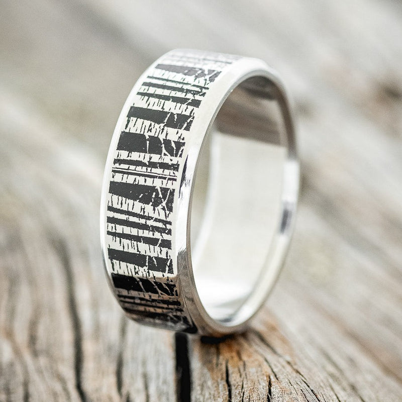 Shown here is "Aspen", a handcrafted, custom embossed men's wedding ring featuring an Aspen forest engraving, upright facing left. It can be customized to feature just about any embossed design you can dream up.