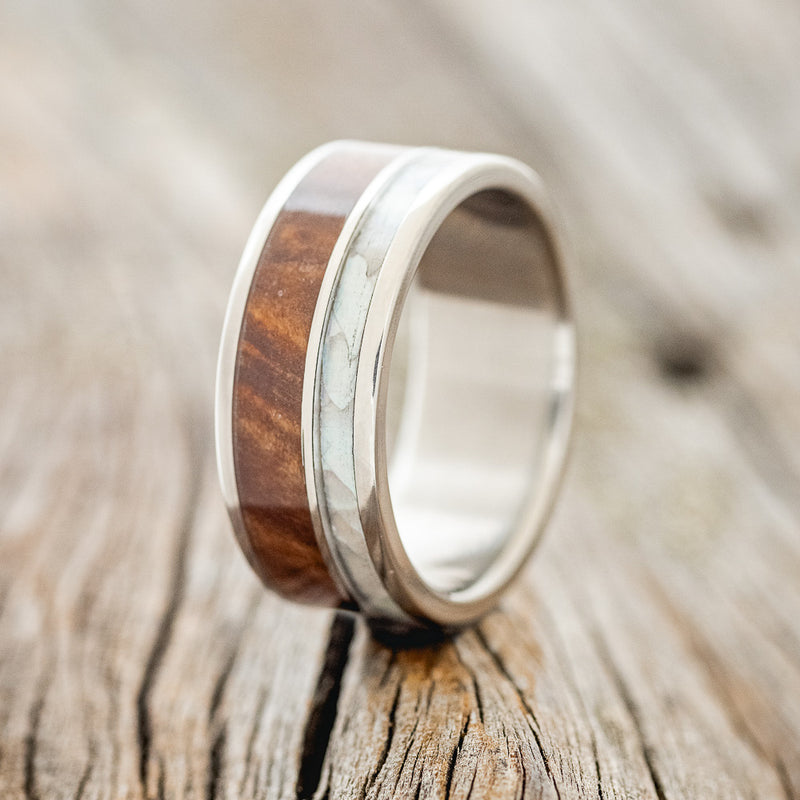 Shown here is "Raptor", a custom, handcrafted men's wedding ring featuring a mother of pearl & redwood inlay, upright facing left.