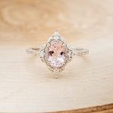 Shown here is "North Star", an oval morganite women's engagement ring with a diamond halo and diamond accents, front facing. Many other center stone options are available upon request.