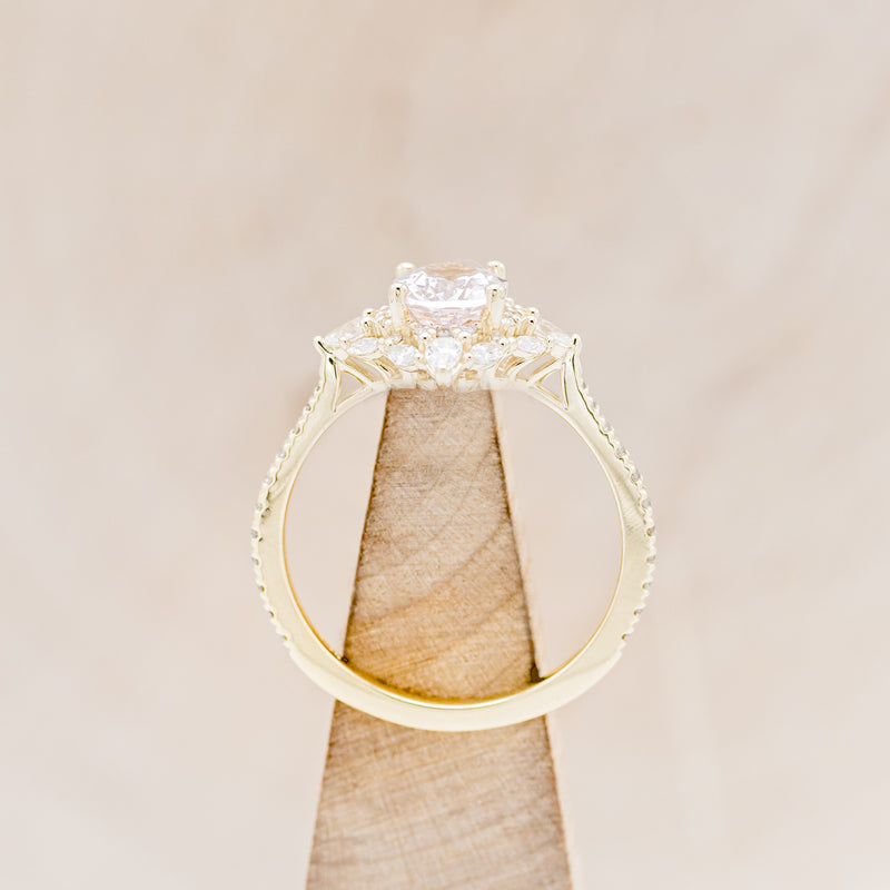 Shown here is "North Star", an oval morganite women's engagement ring with a diamond halo and diamond accents, side view on stand. Many other center stone options are available upon request.