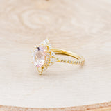 Shown here is "North Star", an oval morganite women's engagement ring with a diamond halo and diamond accents, facing left. Many other center stone options are available upon request.