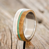 Shown here is "Argos", a custom, handcrafted men's wedding ring featuring whiskey barrel oak and antler overlays with malachite and 14K rose gold inlays, upright facing left. Additional inlay options are available upon request.