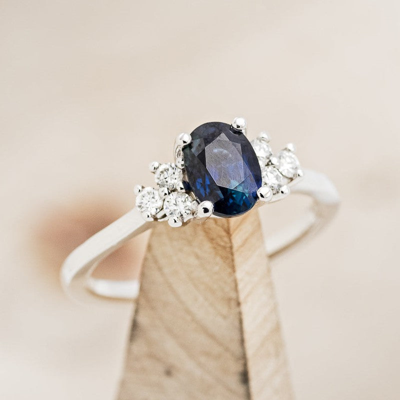 Shown here is The "Gina", an accented oval lab-created sapphire women's engagement ring with delicate and ornate details and is available with many center stone options
