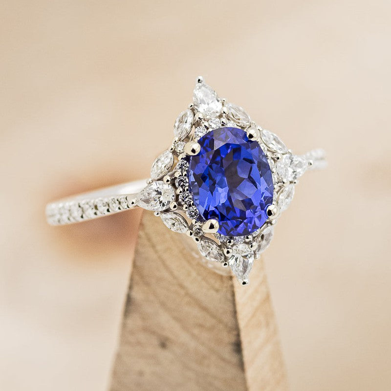 Shown here is The "North Star", a halo-style oval lab-created sapphire women's engagement ring with delicate and ornate details and is available with many center stone options