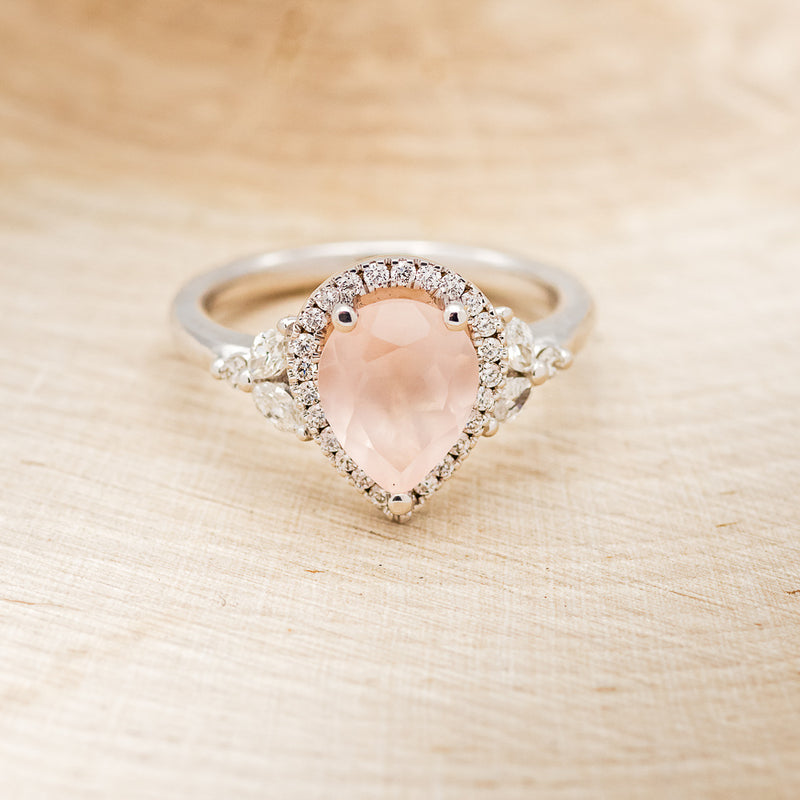 Shown here is "Dream", a rose quartz women's engagement ring with a diamond halo and diamond accents, front facing. Many other center stone options are available upon request.