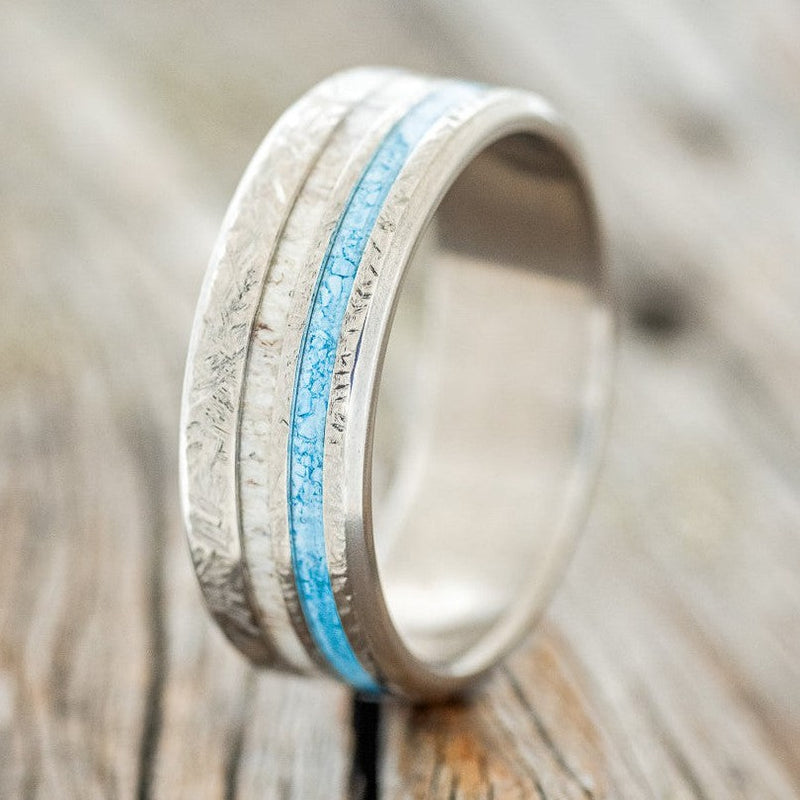 Shown here is "Cosmo", a custom, handcrafted men's wedding ring featuring an elk antler and hand-crushed turquoise offset into two channels and a crosshatched finish, upright facing left. Additional inlay options are available upon request.