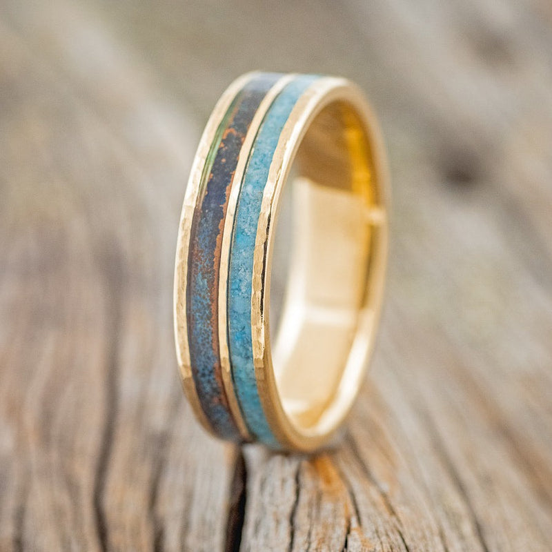 Shown here is "Dyad", a custom, handcrafted men's wedding ring featuring 2 channels with turquoise and patina copper inlays on a thin 14K gold band, upright facing left. Additional inlay options are available upon request.