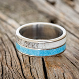 Shown here is "Dyad", a custom, handcrafted men's wedding ring featuring 2 channels with turquoise and antler inlays, laying flat. Additional inlay options are available upon request.