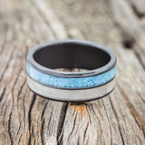 Shown here is "Dyad", a custom, handcrafted men's wedding ring featuring 2 channels with turquoise and antler inlays, shown here on a fire-treated black zirconium band, laying flat. Additional inlay options are available upon request.