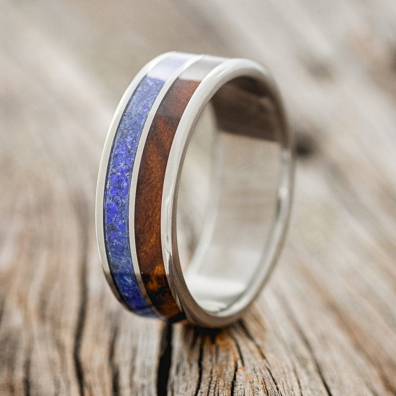 Shown here is "Dyad", a custom, handcrafted men's wedding ring featuring 2 channels with lapis lazuli and ironwood inlays, upright facing left. Additional inlay options are available upon request.