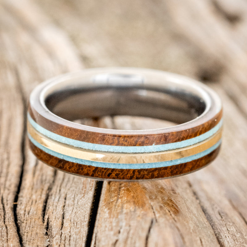  Shown here is "Canyon", a custom, handcrafted men's ring featuring 14K yellow gold and turquoise inlays set between two ironwood overlays, laying flat. Additional inlay and overlay options are available upon request.