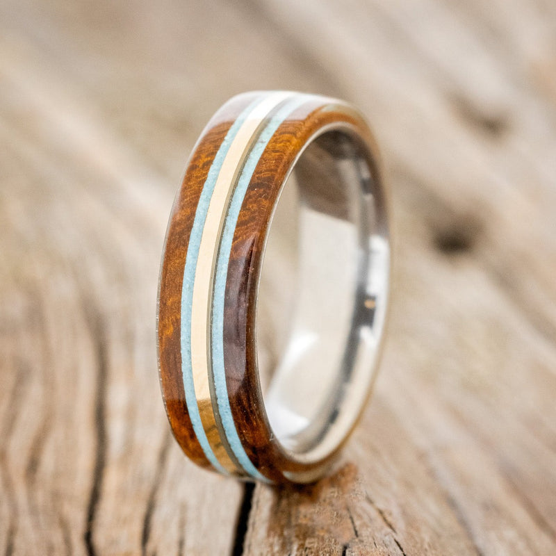Shown here is "Canyon", a custom, handcrafted men's ring featuring 14K yellow gold and turquoise inlays set between two ironwood overlays, upright facing left. Additional inlay and overlay options are available upon request.