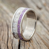 Shown here is "Raptor", a custom, handcrafted men's wedding ring featuring an antler with sugilite and opal mix inlay, upright facing left. Additional inlay options are available upon request.