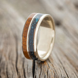 Shown here is "Dyad", a custom, handcrafted men's wedding ring featuring 2 channels with patina copper and ironwood inlays, upright facing left. Additional inlay options are available upon request.