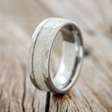 Shown here is a custom, handcrafted men's wedding ring featuring a fire and ice opal inlay on a tungsten band with faceted edges, upright facing left. 