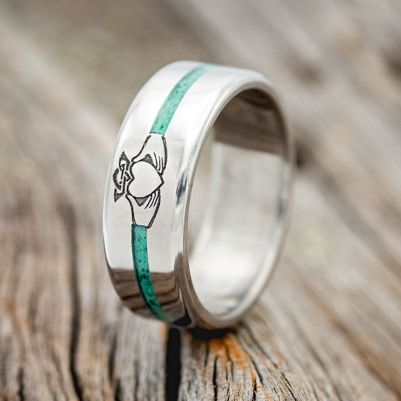 Shown here is a custom engraved Claddagh men's wedding ring featuring malachite inlay, upright facing left. Additional inlay options are available upon request.