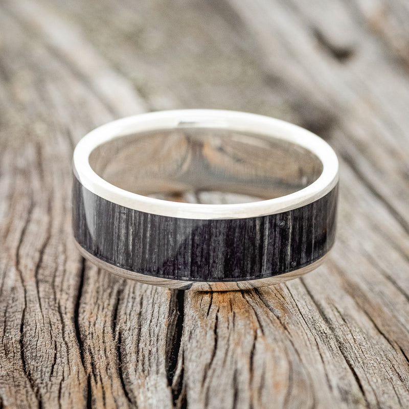 Shown here is "Rainier", a custom, handcrafted men's wedding ring featuring grey birch wood inlay, shown here on a silver band, laying flat. Additional inlay options are available upon request.
