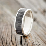 Shown here is "Rainier", a custom, handcrafted men's wedding ring featuring grey birch wood inlay, shown here on a silver band, upright facing left. Additional inlay options are available upon request.