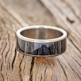 Shown here is "Rainier", a custom, handcrafted men's wedding ring featuring grey birch wood inlay, shown here on a titanium band, laying flat. Additional inlay options are available upon request.