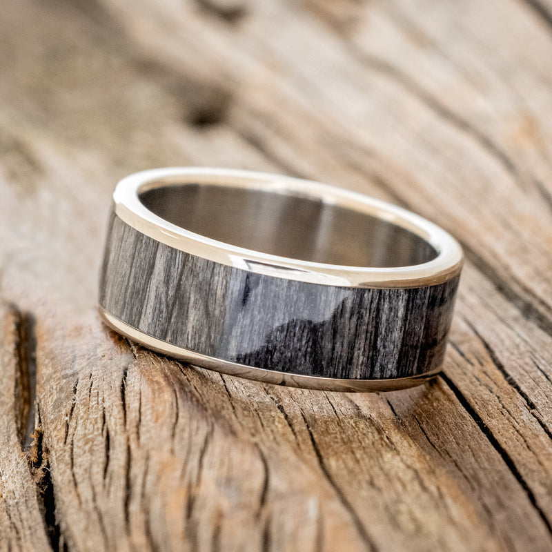 Shown here is "Rainier", a custom, handcrafted men's wedding ring featuring grey birch wood inlay, shown here on a titanium band, tilted left. Additional inlay options are available upon request.