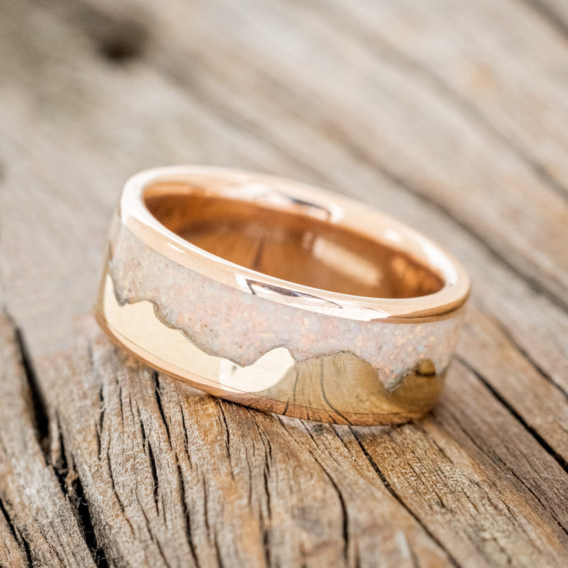 Shown here is "Helios", a custom, handcrafted men's wedding ring featuring a mountain range using pieces of gold and crushed fire & ice opal, tilted left. Additional inlay options are available upon request.