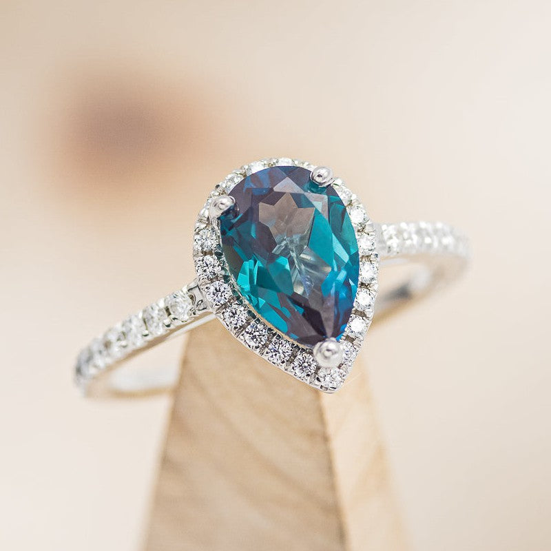 Shown here is a halo-style lab-created alexandrite women's engagement ring with delicate and ornate details and is available with many center stone options