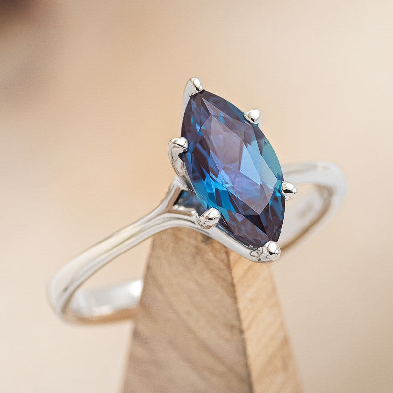 Shown here is a tilted angle of A solitaire-style lab-created alexandrite women's engagement ring with delicate and ornate details and is available with many center stone options