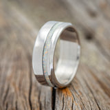 Shown here is "Vertigo", a handcrafted men's wedding ring featuring a fire & ice opal inlay, upright facing left. 