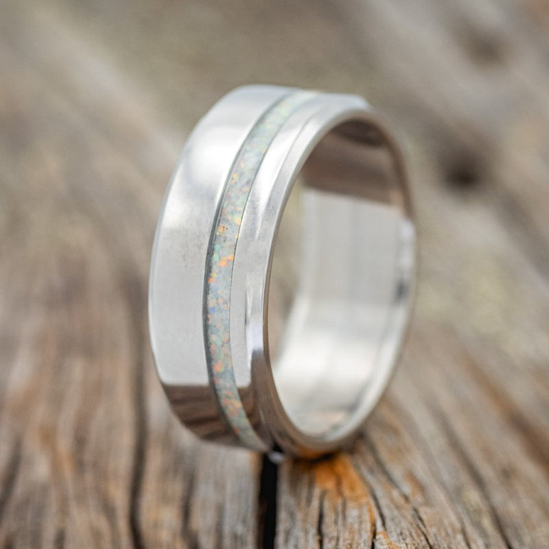 Shown here is "Vertigo", a custom, handcrafted men's wedding ring featuring a fire & ice opal inlay, upright facing left. Additional inlay options are available upon request.